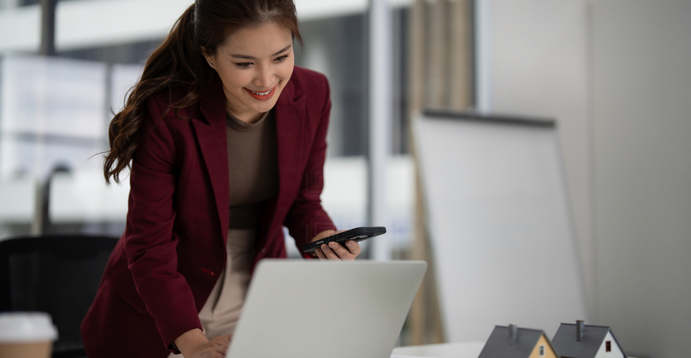 Homebuilder salesperson smiles as she reviews leads on her laptop